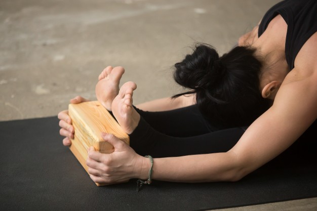 young-attractive-woman-in-paschimottanasana-pose-with-block-clo_1163-3065